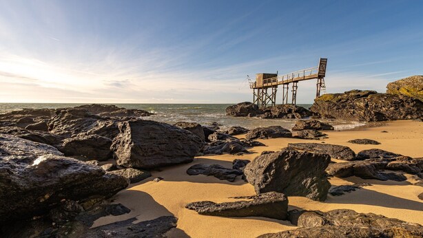 A rocky beach with a wooden pier structure.