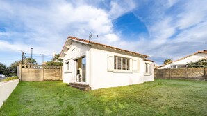A single-story house with a tiled roof, a small front porch, and a well-maintained lawn.