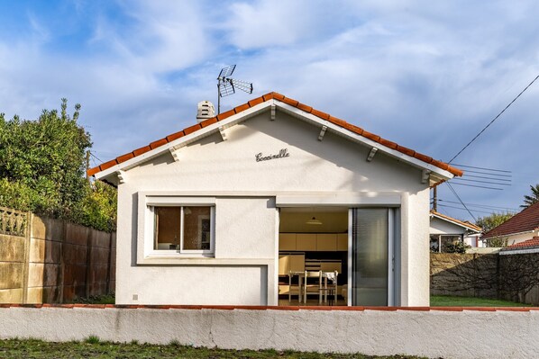 Una casa de un piso con fachada blanca, tejado rojo y chimenea visible.
