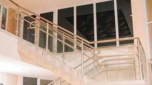 A multi-level interior with a curved sofa, a staircase with glass railings, and a ceiling with woven light fixtures. - BALI MAR HOTEL (Natal)
