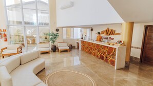 A spacious hotel lobby with a modern design, featuring a reception desk, seating area, and large windows. - BALI MAR HOTEL (Natal)
