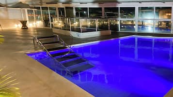 A swimming pool with a glass barrier and steps leading into it.