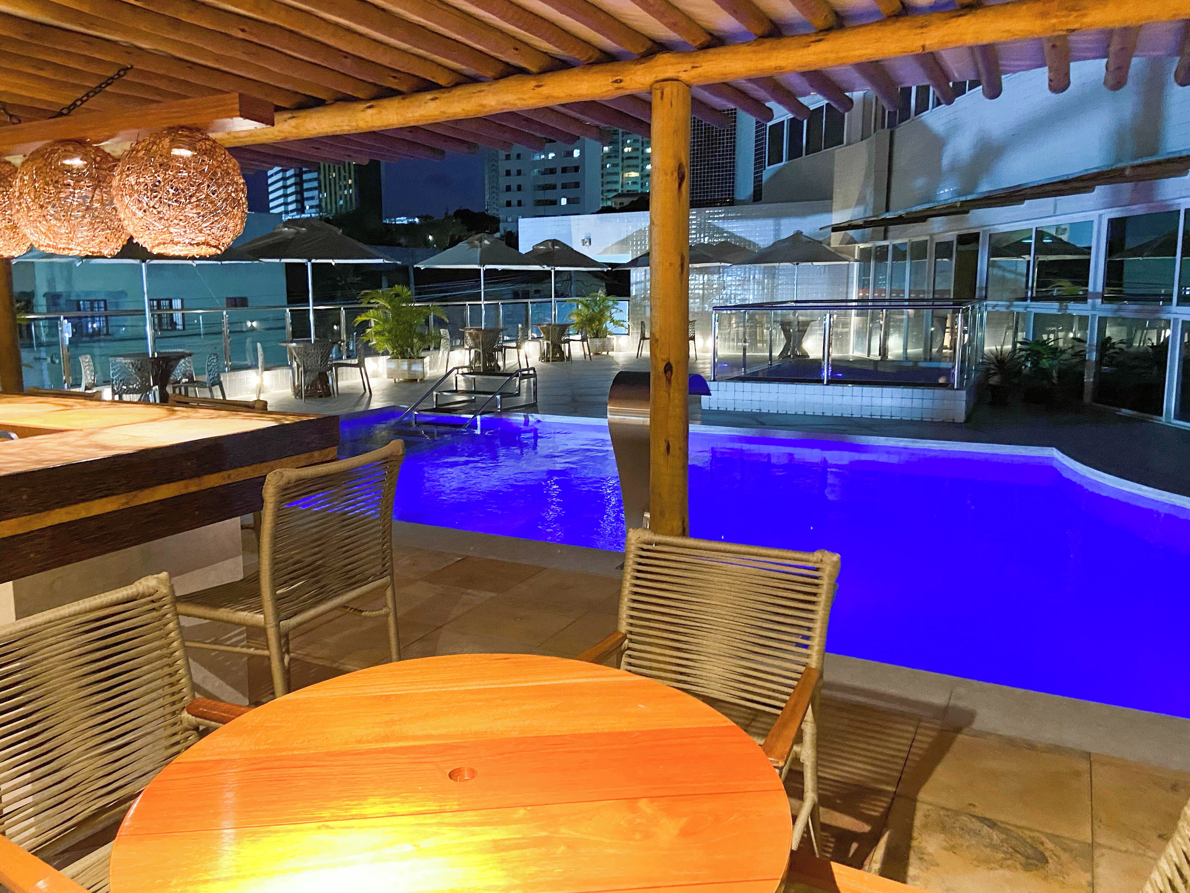 An outdoor pool area with a wooden deck, lounge chairs, and a bar area.