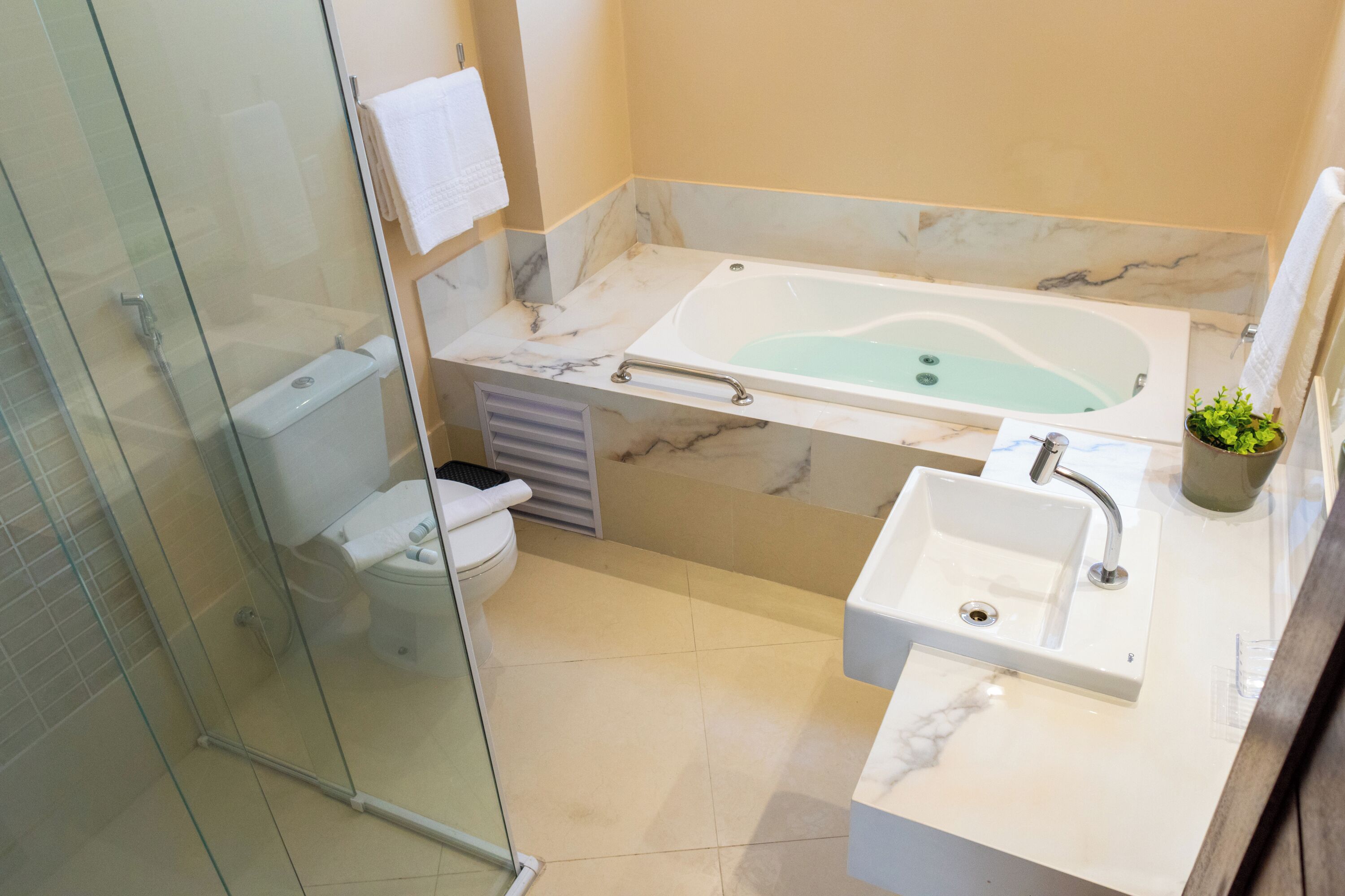 A modern bathroom with a glass-enclosed shower, a marble sink, and a freestanding bathtub.