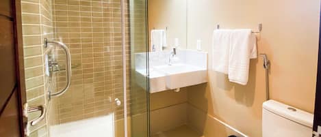 A modern bathroom with a glass-enclosed shower, a white sink, and a toilet.