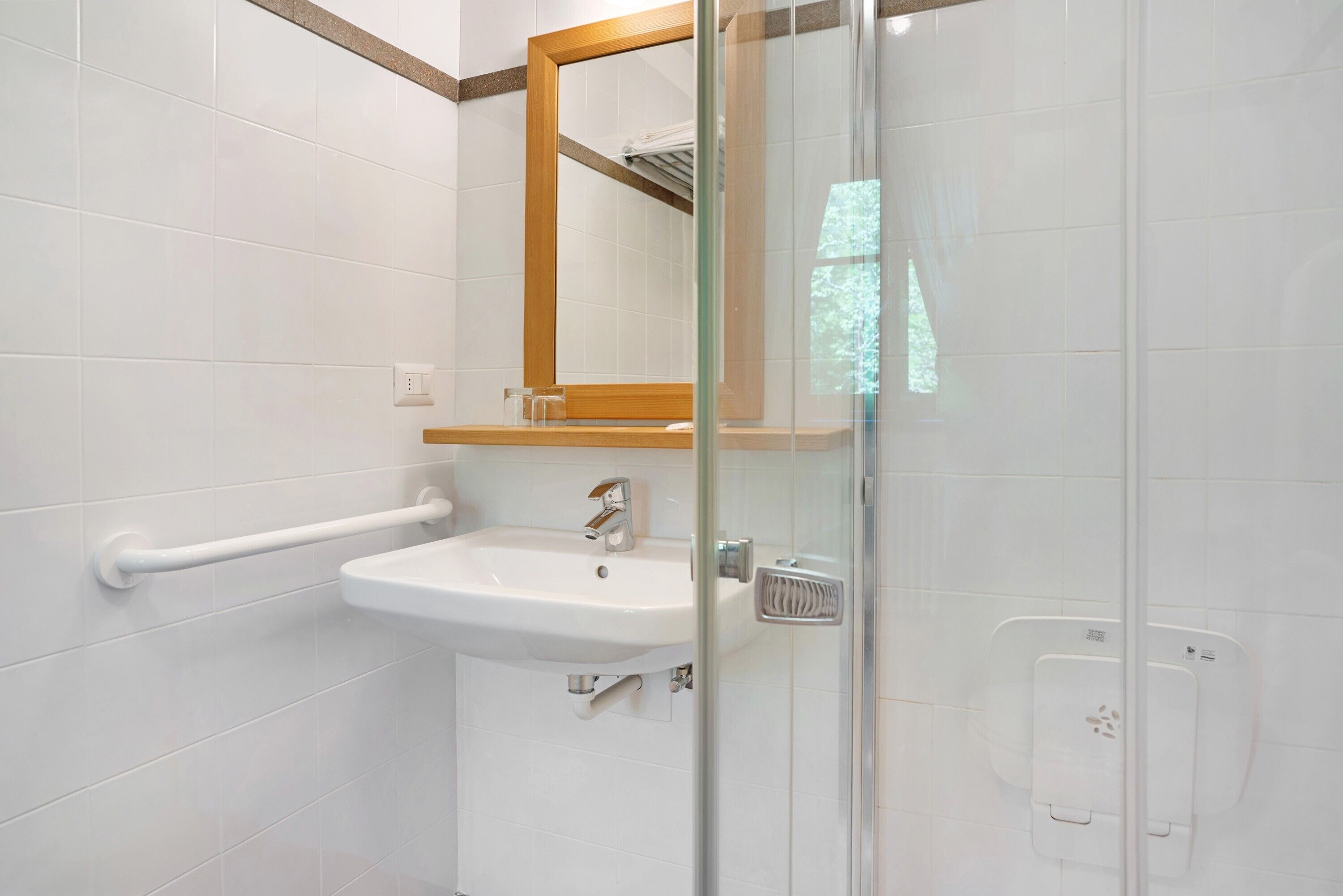 Een badkamer met een wit wastafelmeubel, een spiegel en een douchecabine van glas.