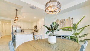 A modern kitchen with white cabinets, stainless steel appliances, and a wooden dining table with chairs. - Ibis Landing Golf Club On-Site: Condo w/ Porch! (Lehigh Acres)