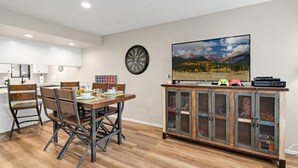 A modern living room with a dining area, a large flat-screen TV, and a vintage cabinet. - County Club Townhome *Packman Game, Xbox, Golf course Views, Near Forest Edge (Flagstaff)