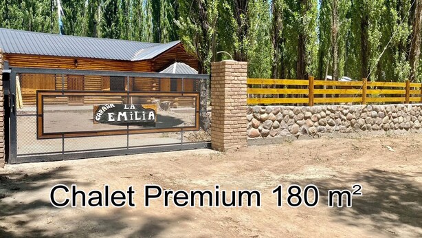 A wooden chalet with a metal gate and a sign reading "La Casa de Emilia."