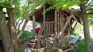 A rustic wooden structure with a stone foundation, surrounded by trees and greenery. - Room 'La Gemma - Suite Incantata' with Mountain View, Shared Garden and Wi-Fi (Sant'Orsola Terme)