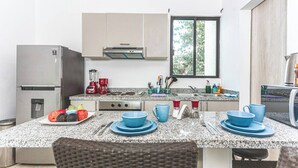 Cozinha moderna com bancada de granito, eletrodomésticos de aço inoxidável e área de jantar com louças azuis.