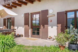 Un bâtiment doté de volets en bois, d’une entrée en pierre et de plantes en pot.