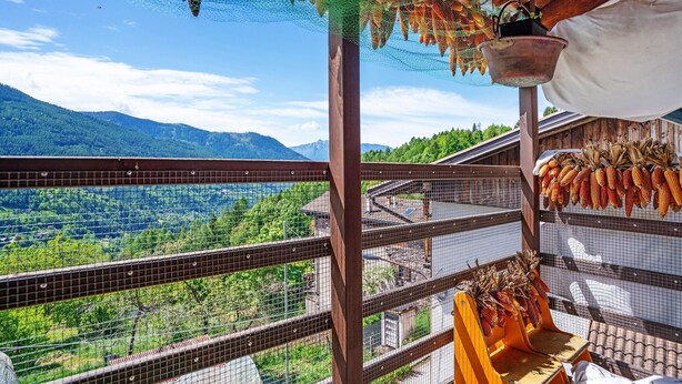 A balcony with a view of a mountainous landscape, a hanging basket with dried corn, and a metal railing. - Room 'Lagemma-stanza Dei Mirtilli' with Mountain View, Shared Garden and Wi-Fi (Sant'Orsola Terme)