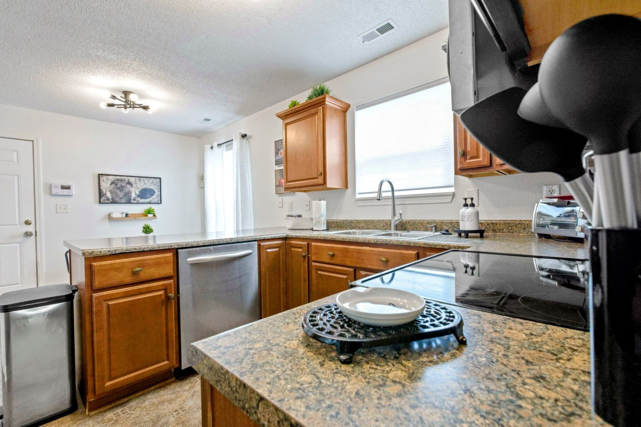 A kitchen with granite countertops, wooden cabinets, a stainless steel dishwasher, and a black stove.