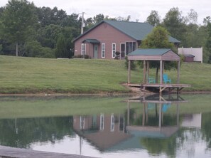 A house with a green roof, a wooden deck, and two blue chairs.