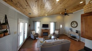 Ein geräumiges Wohnzimmer mit Holzbalkendecke, Kamin und Wandfernseher.