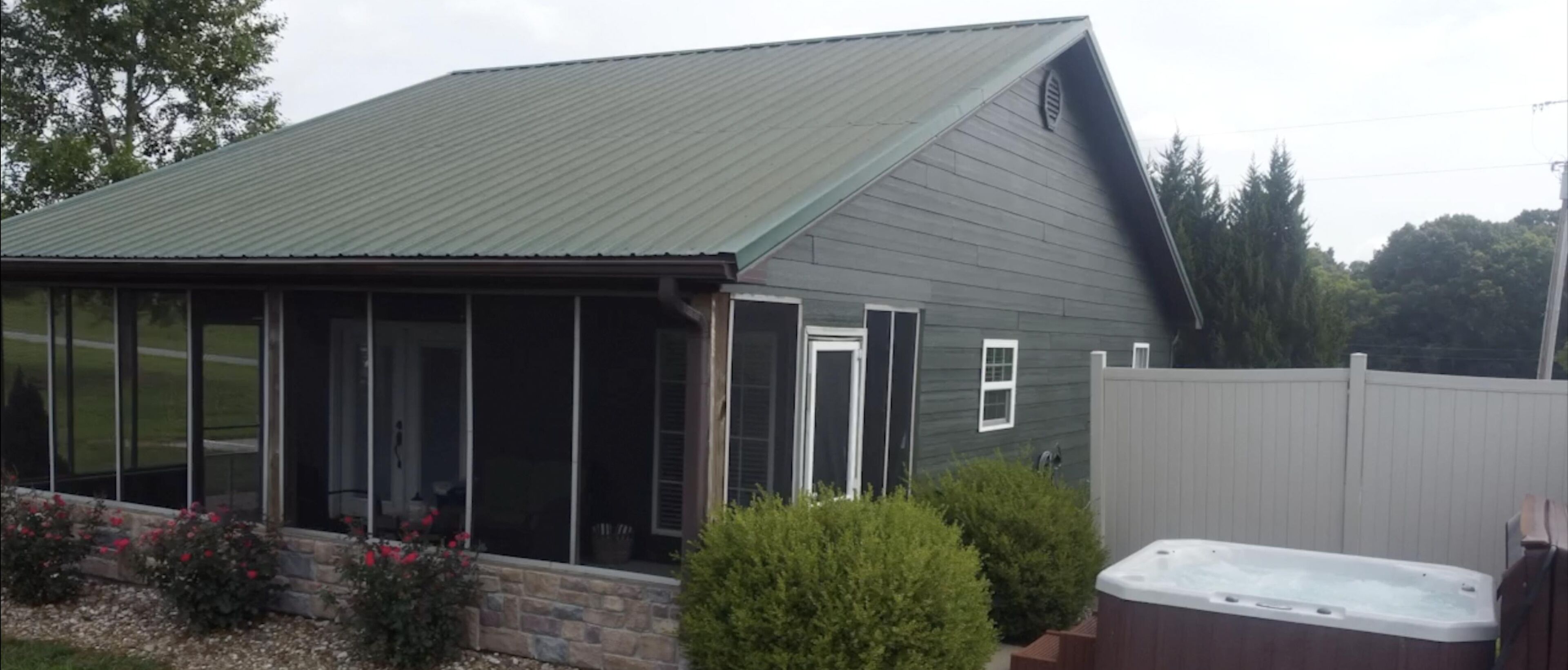 A house with a covered patio, a hot tub, and a fenced yard.