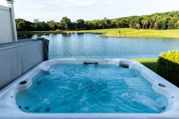 A hot tub with a view of a lake and surrounding greenery.