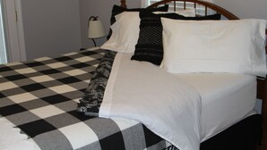 Ein Bett mit kariertem Überwurf, einem Holz-Kopfteil und einer Nachttischlampe.