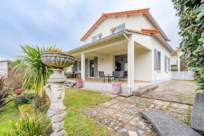 A house with a covered porch, stone tiles, and potted plants.