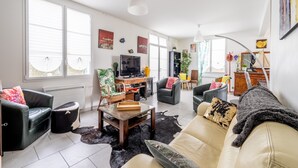 Un salon moderne comprenant un canapé, des fauteuils, une table basse et un téléviseur.