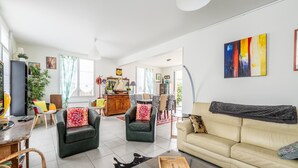 Un salon spacieux comprenant un canapé, des fauteuils, une table basse et un coin repas.