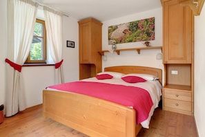 Une chambre à coucher avec un lit en bois, une table de chevet, une étagère avec une lampe et un tableau accroché au mur.