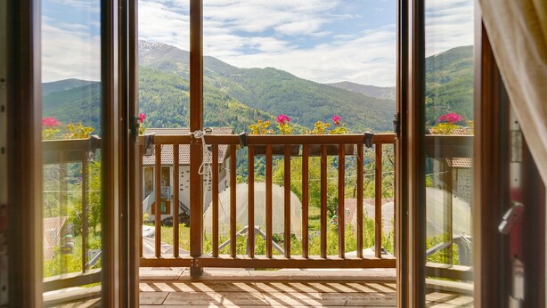 Un balcon avec vue sur les montagnes et un ciel dégagé.