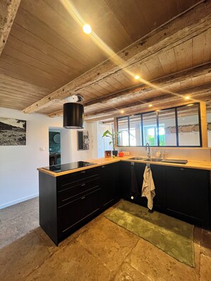 A modern kitchen with black cabinets, a wooden countertop, and a large window. - Gîte " La Grange d'Annalys " 13 people (Granges-Narboz)