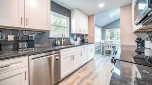 Una cocina moderna con electrodomésticos de acero inoxidable, armarios blancos y un backsplash de azulejos negros.