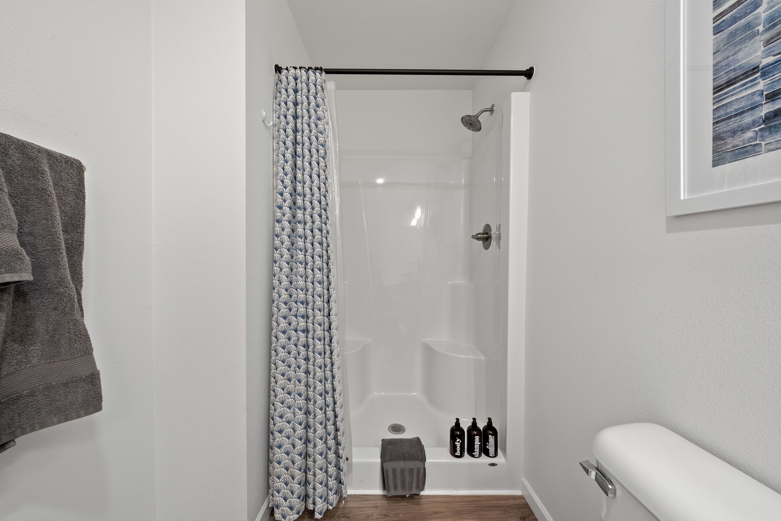 A bathroom with a shower, a towel rack, and a framed picture on the wall.