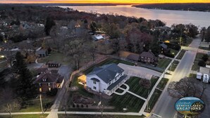 An aerial view of a residential area with houses, a large white building, and a lake.