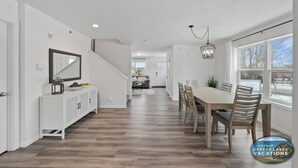 A spacious kitchen with a dining area, wooden flooring, and a view of the outdoors.