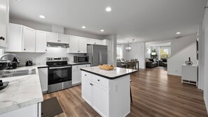 A modern kitchen with white cabinetry, stainless steel appliances, and a marble countertop. - The Blackstone| Arcade and Game Lounge|Near Downtown|New Construction|Groups Welcome! (Lake Geneva)