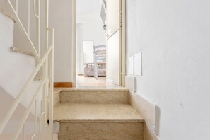 Una escalera que lleva a una habitación con una cama y una silla.