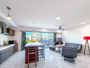 A modern living space with a kitchen, dining area, and seating area. - 2BR Condo w/Rooftop Pool (Isla Mujeres)