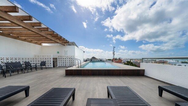 A rooftop pool area with lounge chairs and a view of the sea. - 2BR Condo w/Rooftop Pool (Isla Mujeres)