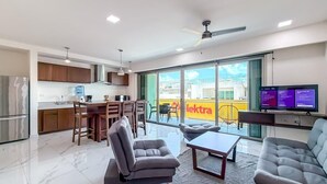 A modern living room with a sofa, armchair, and dining area. - 2BR Condo w/Rooftop Pool (Isla Mujeres)