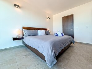 A modern bedroom with a large bed, bedside tables, a wardrobe, and a wall-mounted light fixture. - 1BR PH Downtown w/Rooftop Pool (Isla Mujeres)