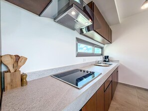 A modern kitchen with a built-in stove, wooden utensils, and a window above the sink. - 1BR PH Downtown w/Rooftop Pool (Isla Mujeres)