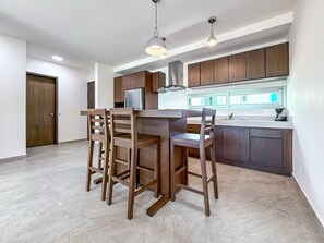Une cuisine moderne avec des meubles en bois, un réfrigérateur en acier inoxydable et un coin bar avec des tabourets.