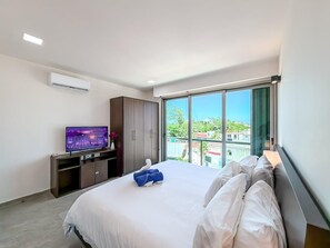 A hotel room with a large bed, a TV on a stand, a wardrobe, and a balcony with a view. - 1BR w/Rooftop Pool Downtown (Isla Mujeres)