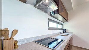 A modern kitchen with a built-in stove, a sink, and wooden utensils on the counter. - 1BR w/Rooftop Pool Downtown (Isla Mujeres)