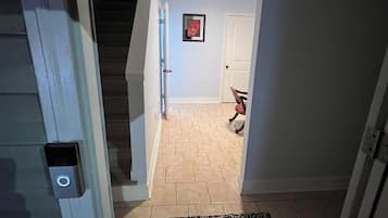 Un couloir avec un tapis à motifs, une porte et un escalier.