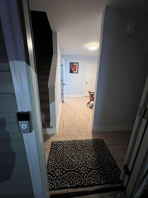 A hallway with a patterned rug, a door, and a staircase. - House with JACUZZI * Luxury * 3BR. { ExclusiveDiscounts } (Charlotte)