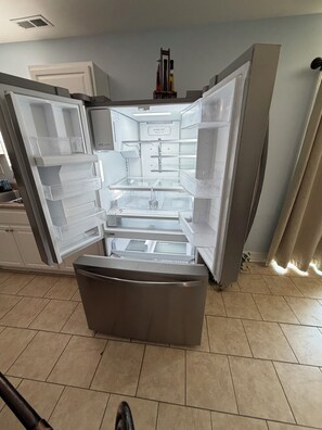 An open refrigerator with multiple shelves and drawers, a water dispenser, and a control panel. - House with Jacuzzi * Luxury * 3 bedrooms. { Exclusive Discounts } (Charlotte)