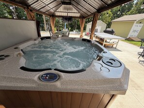 A hot tub with a control panel, surrounded by outdoor furniture and a covered patio area. - House with Jacuzzi * Luxury * 3 bedrooms. { Exclusive Discounts } (Charlotte)