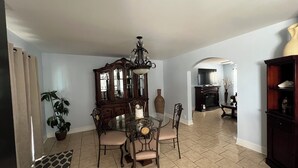 A dining area with a wooden table and chairs, a chandelier, and a large mirror above the table.