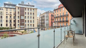 A balcony with a glass railing overlooking a cityscape with multi-story buildings. - Muinoa 2 by FeelFree Rentals (San Sebastián)