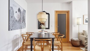 A dining area with a dark wooden table, six woven chairs, a hanging lamp, and a large map on the wall. - Muinoa 2 by FeelFree Rentals (San Sebastián)